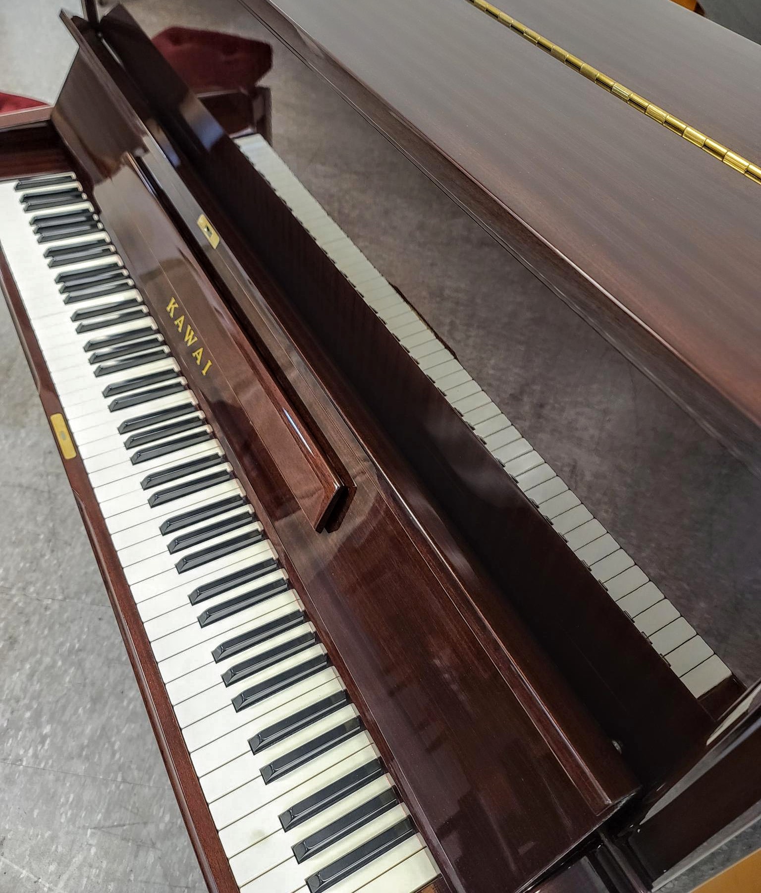 Beautiful Kawai professional upright piano profiled front view. Has beautifully grained custom wood case.